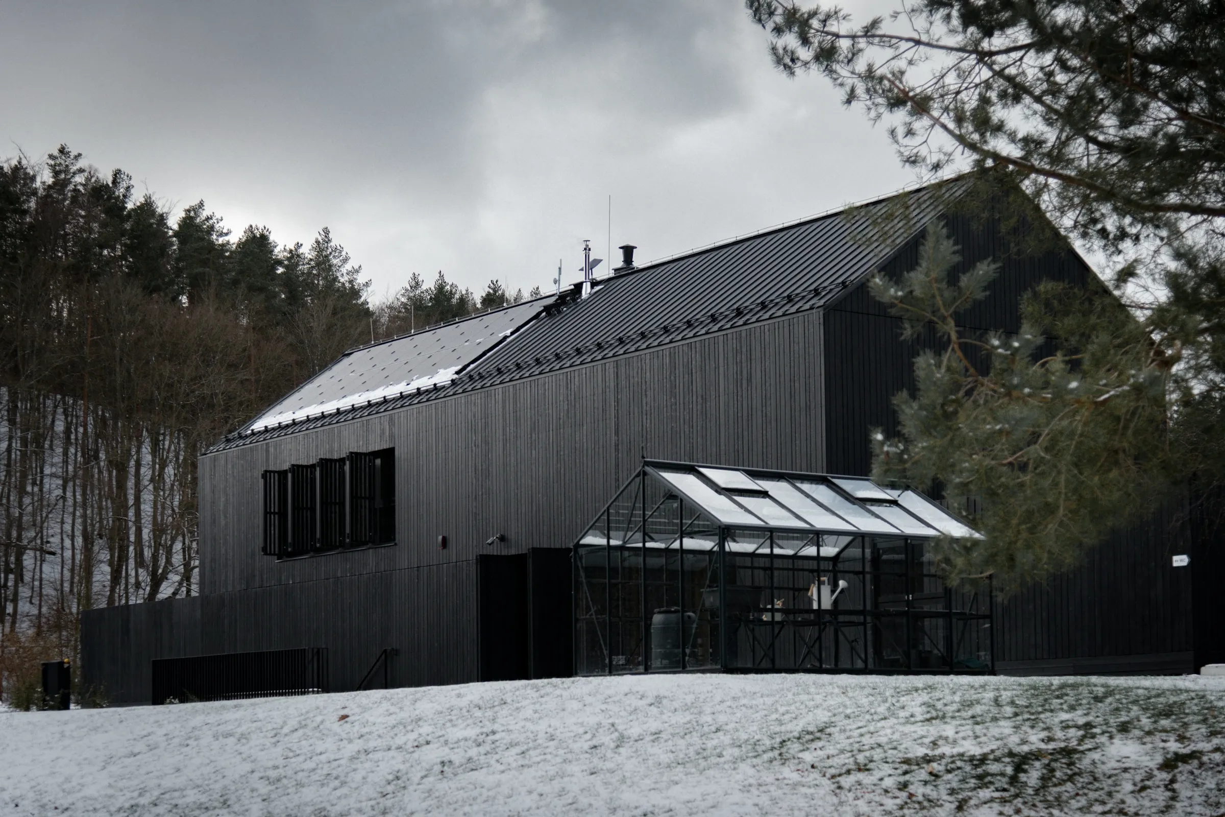 Maison Lisière : maison sombre aux grandes baies en bordure de forêt